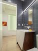 Modern home with Bath Room, Light Hardwood Floor, Accent Lighting, Ceramic Tile Wall, and Two Piece Toilet. Previously, a window of frosted glass block punctuated the hallway. Unfortunately, it overlooked a perpetually dark courtyard and illuminated nothing. I changed this into an art installation of light. With its multiple settings, one can rotate through a selection of colors to wash the space in colored light, instantly changing the mood and feel of the space. The portal is seen here in lime green. Photo 3 of Art and Light