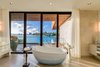 A freestanding tub sits in the center of the master bathroom suite with views of the bay. Photo 16 of North Bay Road Residence modern home