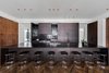 In the kitchen, matte-finish oak cabinetry, a black countertop and black backsplash provide a masculine, monochromatic feel. Photo 4 of Ponce Davis Residence modern home