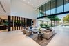 Modern home with Living Room, Sofa, End Tables, Coffee Tables, Chair, Ceiling Lighting, Recessed Lighting, Ribbon Fireplace, and Limestone Floor. Vertical wood elements separate the main living room from the kitchen area, while still emphasizing openness. Photo 4 of Palm Island Residence