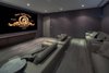 Modern home with Living Room, Sofa, Medium Hardwood Floor, and Recessed Lighting. The home's modern theater room offers stadium-style seating with leather couches and wood flooring. Photo 9 of Palm Island Residence