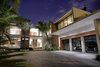 Modern home with Hardscapes, Trees, Front Yard, Walkways, Raised Planters, Large Patio, Porch, Deck, Shrubs, Stone Patio, Porch, Deck, Landscape Lighting, Garage, and Attached Garage Room Type. The front entrance of the residence features an abundance of natural stone, stained Ipe wood, and a 3-car garage suite with glass doors. Photo of Casa Ischia