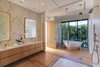 Modern home with Bath Room, Marble Counter, Light Hardwood Floor, Wall Mount Sink, Freestanding Tub, Enclosed Shower, Recessed Lighting, and Marble Wall. The master bath features dual vanities, a stand-alone tub, and a glass-enclosed shower. Photo 7 of Casa Ischia