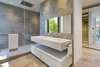This bathroom features an expansive glass-enclosed shower and unique concrete stamped wall. Photo 13 of Rivo Alto Residence modern home