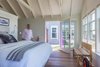 A modest bedroom sits functionally askew to the main part of the cottage to provide a panoramic view of Provincetown harbor - a spectacular view of twinkling nighttime shore lighting as the dunes curve toward the tip of Cape Cod. The open french door leads to a secluded hot tub and deck area. Photo 5 of Corkin House modern home