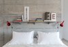 a viroc shelf on the concrete wall is used as a bed table behind the bed. Red pair of vintage lamps from the Lisbon flea market Féria de Ladra Photo 18 of micasaenlisboa modern home