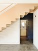 Modern home with Hallway and Concrete Floor. On a sloped plot in the Echo Park neighborhood of Los Angeles, an almost 100-year-old anonymous bungalow was rendered in pink, referencing the sun-kissed stucco that's so common in the region.
Mexico City-based architecture firm PRODUCTORA completely remodeled and renovated the home of graphic designer Jessica Fleischmann, daughter of Ernst Fleischmann, who led the Los Angeles Philharmonic and commissioned Frank Gehry to build the Walt Disney Concert Hall. Over the 15 years she lived in the home, she developed a strong connection to the neighborhood and the house itself, which inspired her to renovate it. With her strong affinity for design, she was thoroughly involved in the creative process, including selecting the particular colors that are interspersed throughout the renovation and extension of the house. Photo 6 of Jessica Fleischmann’s Echo Park Bungalow