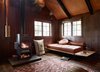Modern home with Living Room, Wood Burning Fireplace, and Sofa. Agate Pass Cabin | A floor pillow made from a vintage Japanese mailbag | Glulam engineered plywood is used throughout the project, including Maskin’s design for a daybed | Artwork: Last Stand: Cedar by Karen Rudd is a cardboard portrait of a tree felled by lumberjacks in the clearcut of an Olympic Peninsula forest. Maskin purchased the piece to recall the clear cutting of trees in his region, and the controversial cutting down of a tree on his property. Photo 9 of Agate Pass Cabin