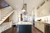 Modern home with Stone Counter, Bar, Ceiling Lighting, Stools, Pendant Lighting, Dark Hardwood Floor, White Cabinet, Refrigerator, Wall Oven, Cooktops, Range Hood, Dishwasher, Microwave, Undermount Sink, Staircase, Wood Railing, and Wood Tread. Bickford Park - Kitchen Photo 10 of Bickford Park