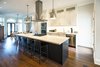 Modern home with Kitchen, Dark Hardwood Floor, Stone Counter, White Cabinet, Ceiling Lighting, Pendant Lighting, Range Hood, Range, Microwave, Wall Oven, and Cooktops. Bickford Park - Kitchen Photo 12 of Bickford Park