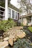Boulders, a water feature and a river path were created in the front yard to enhance the asian flair this home had. Landscape lighting was installed to ensure that the home felt warm even at night. Photo 10 of Asian Bungalow modern home