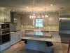 What had once been a dark 1950's style kitchen, being shut off from the rest of the home, was opened up to allow for greater integration with the rest of the home, updated appliances and fixtures and a lighter, more airy workspace for this critical "hub" in the home. A lower shelf was designed for the island specifically with the needs of their daughter in mind - allowing her to become a part of the family no matter where in the house she was. Photo of ADA Kitchen modern home