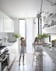Modern home with Kitchen, Marble Counter, White Cabinet, Stone Slab Backsplashe, Ceiling Lighting, Wall Lighting, Refrigerator, Dishwasher, Ice Maker, Light Hardwood Floor, Undermount Sink, Wall Oven, and Range. Honed Carrara marble lines the kitchen countertops as well as the backsplash. Photo 8 of Little House. Big City.