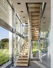 Modern home with Staircase and Wood Tread. Set among fields along the south facing coast of Long Island and within a short walk to the ocean, this Hamptons residence is a quiet refuge for a growing family. Architect Bohlin Cywinski Jackson says that “a suspended bridge spans through the double-height space, connecting second story volumes at varying levels and inclining upward and terminating at either end in an open staircase.” Photo 16 of Hamptons Residence
