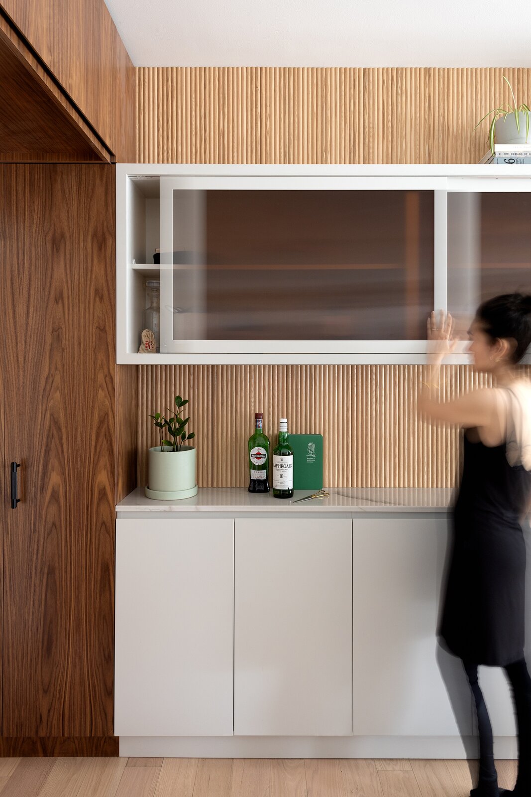 Leah selected light-diffusing sepia-toned reeded glass for some of the upper cabinets because "you can store anything inside and not see any distracting shapes or colors. It feels like old glass from an apothecary, and it ties together the warmth in the oak floor and walnut cabinetry."