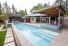 The pool is surrounded by a generous terrace and features a covered hot tub and seasonal kitchen. Photo 12 of Cedar Mills House modern home