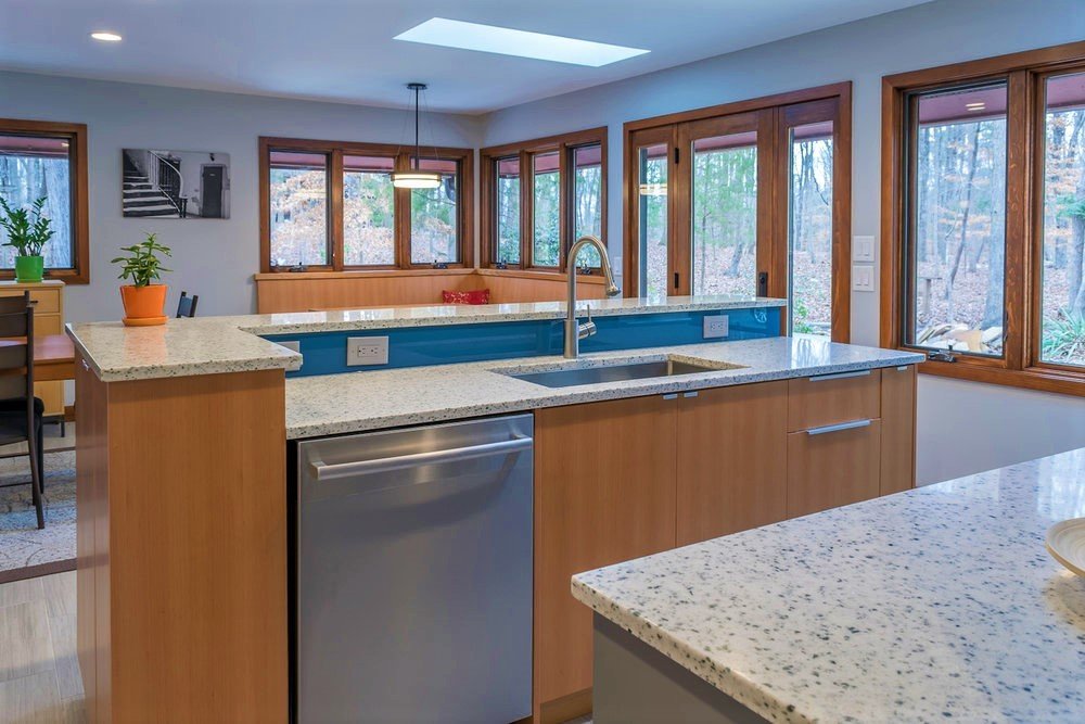 A wall of JELD-WEN Siteline windows makes for a stunning view from this island sink, featuring custom fir cabinetry, glass backsplash and granite counters.