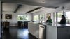 The spacious kitchen is sensible but definitely not boring with glossy white counter tops and cabinets that contrast with the dark flooring. Photo 4 of Mod Remodel modern home