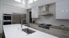 A neutral color palette is modernized with glossy finishes, a subway tile backsplash, and stainless appliance accents. This is a kitchen that will highlight and draw attention to the food, becoming a blank canvas for the owners to personalize. Photo 5 of Modern Courtyard Home modern home