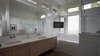 The master bathroom is a light-filled space of relaxation with a large bathtub as well a spacious shower. The tile backsplash provides a modern finish and every convenience was added to truly make this a room of leisure. Photo 6 of Modern Courtyard Home modern home