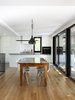 Modern home with Chair, Track Lighting, Ceiling Lighting, Table, Medium Hardwood Floor, Pendant Lighting, Light Hardwood Floor, Ceramic Tile Floor, Ceramic Tile Backsplashe, Wall Oven, White Cabinet, Undermount Sink, Cooktops, and Dining Room. Dining room - Rue de l'Espéranto residence - Guillaume Sasseville & PARKA - Architecture & Design Photo 3 of Rue de l'Espéranto residence