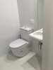 A simple minimalist bathroom; toilet, sink with mirror, and shower opposite. Photo 5 of The Tiny house modern home
