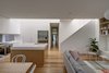 Modern home with Kitchen, Engineered Quartz Counter, White Cabinet, Medium Hardwood Floor, and Ceiling Lighting. Interior spaces are simple and understated. Natural timber in light tones contrasts with white walls, lit by washes of sunlight. Photo 3 of Inner West House