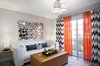 The home office area was meant to be a refuge and the place where our client would spend a lot of time both working and relaxing. It needed to be bright and airy, modern, but comfortable. We used neutral grey paint on the walls, bold chevron curtains, and bespoke whitewash wood floors. The orange and bronze accents throughout were brought in in order to contrast against the black, white and grey main elements of the space. Two modern end tables on either side of the sofa with Zebra wood tops, also offer a touch of warmth and contrast. Photo 4 of West Coast Pied A Terre modern home