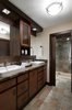 In the master bathroom, we went for a much more earthy, and rustic look. Using a porcelain slate tile with lots of nice variation in it, we made this the element that connected both the vanity area and the shower room, and used it on the floors as well as the walls. The sink vanity was a custom designed and built unit with a Brown Forest Marble top and lots of storage space! Minimal, white vessel sinks completed the look, and added a more modern touch.
The pocket door was added, and stained to match the vanity area. Moving into the shower and toilet room, the main element here was the highly textured and varied tile. We accented this with a teak floor in the shower, and some rustic, live edge wood shelves above the toilet. Again, we used more modern fixtures and lighting to contrast against the rustic materials.
Photo 6 of West Coast Pied A Terre modern home