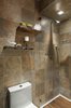 In the master bathroom, we went for a much more earthy, and rustic look. Using a porcelain slate tile with lots of nice variation in it, we made this the element that connected both the vanity area and the shower room, and used it on the floors as well as the walls. The sink vanity was a custom designed and built unit with a Brown Forest Marble top and lots of storage space! Minimal, white vessel sinks completed the look, and added a more modern touch.
The pocket door was added, and stained to match the vanity area. Moving into the shower and toilet room, the main element here was the highly textured and varied tile. We accented this with a teak floor in the shower, and some rustic, live edge wood shelves above the toilet. Again, we used more modern fixtures and lighting to contrast against the rustic materials.
Photo 5 of West Coast Pied A Terre modern home