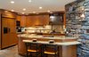 The cabinetry was custom designed and built out of cherry wood, and accented with oil rubbed bronze hardware. The counter tops are a rich golden sea granite, which is the same material used in the main dining room that connects to the kitchen where the bar is located.
A hammered copper vent over the range, as well as a hammered copper farm sink, added a rustic, handmade appeal to the kitchen. The backsplash is a mix of tumbled jerusalem gold stone, with a border throughout that pops up over the range area. The border is made up of 2 burnished metal pencil liner tiles, with a square, multi color glass mosaic in the center.
Photo 2 of Artisan Kitchen for a Nature Loving Family modern home
