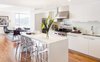 A bright kitchen with a mirrored island & acrylic barstools add a glossy touch Photo of Atwater modern home