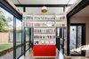 The home office/ guest room is defined by a free standing library and storage element with sliding door panels. A modest courtyard element provides additional natural light and ventilation. Photo 11 of Enmore House modern home