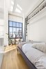 The bedroom previously had floor-to-ceiling shelving with a library ladder. The storage was scaled back with open shelving across the length of the room. Photo 3 of A Greenwich Village Loft Gets a Makeover modern home