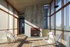 Modern home with Light Hardwood Floor and Chair. “The fireplace extends the season,” says Ryall. “The owners probably use that porch six months out of the year.” The design team formed the fireplace’s concrete facade using rough wood boards to give it a rugged texture. Photo 12 of Orient House V