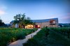 Modern home with Outdoor, Trees, Front Yard, Walkways, Hardscapes, and Gardens. Tasked with creating a multi-use guest pavilion on a relatively small Northern California vineyard lot that could also host sit down dinners for up to 60 people, designers at Anderson Architects started by asking the key questions: “Where should it be within the property?” “How much floor area do we need for a 60 person dinner?” “How much volume do we need for a basketball court?” “We also always tell ourselves to look at the landscape first, let it dominate and lead it through. The building took the form of a large Napa Valley barn. Photo of Napa Barn