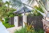 Modern home with Outdoor, Trees, Grass, Shrubs, Front Yard, Hardscapes, Pavers Patio, Porch, Deck, Large Patio, Porch, Deck, Metal Fences, Wall, Walkways, Horizontal Fences, Wall, Landscape Lighting, and Garden. The Bismarckia Palm was not only used as a focal point but it also blocks the view of the neighbors into the cantilevered office. The step up into the property was done as the grade had to be made up between the street and the house therefore it was done gradually by adding the first step up into the property. Photo 2 of Key West Modern