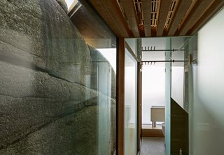 The glass wall forces focus on the texture of the surrounding cliffs.