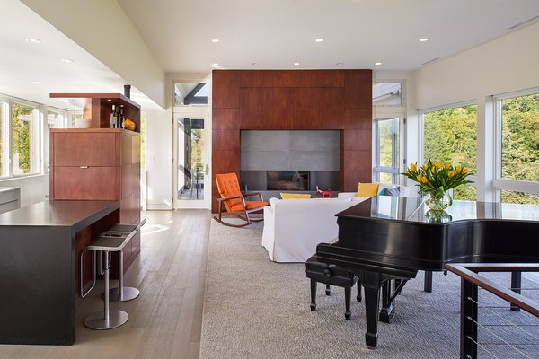 Expansive windows on both sides of the open living area bring the outside in. Marvin doors, the Ultimate Swinging French door, flank the mahogany-wrapped fireplace and provide easy access to the screened porch. 