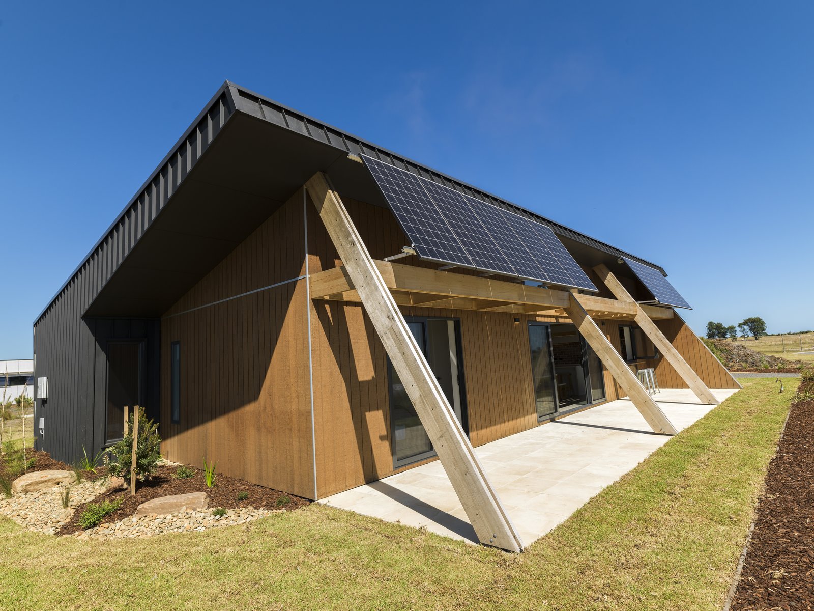 A "raked roof" promotes daylighting, while a 6Kw photovoltaic solar array with 4.8Kw battery storage generates clean energy. The front porch encourages socializing with the neighbors.