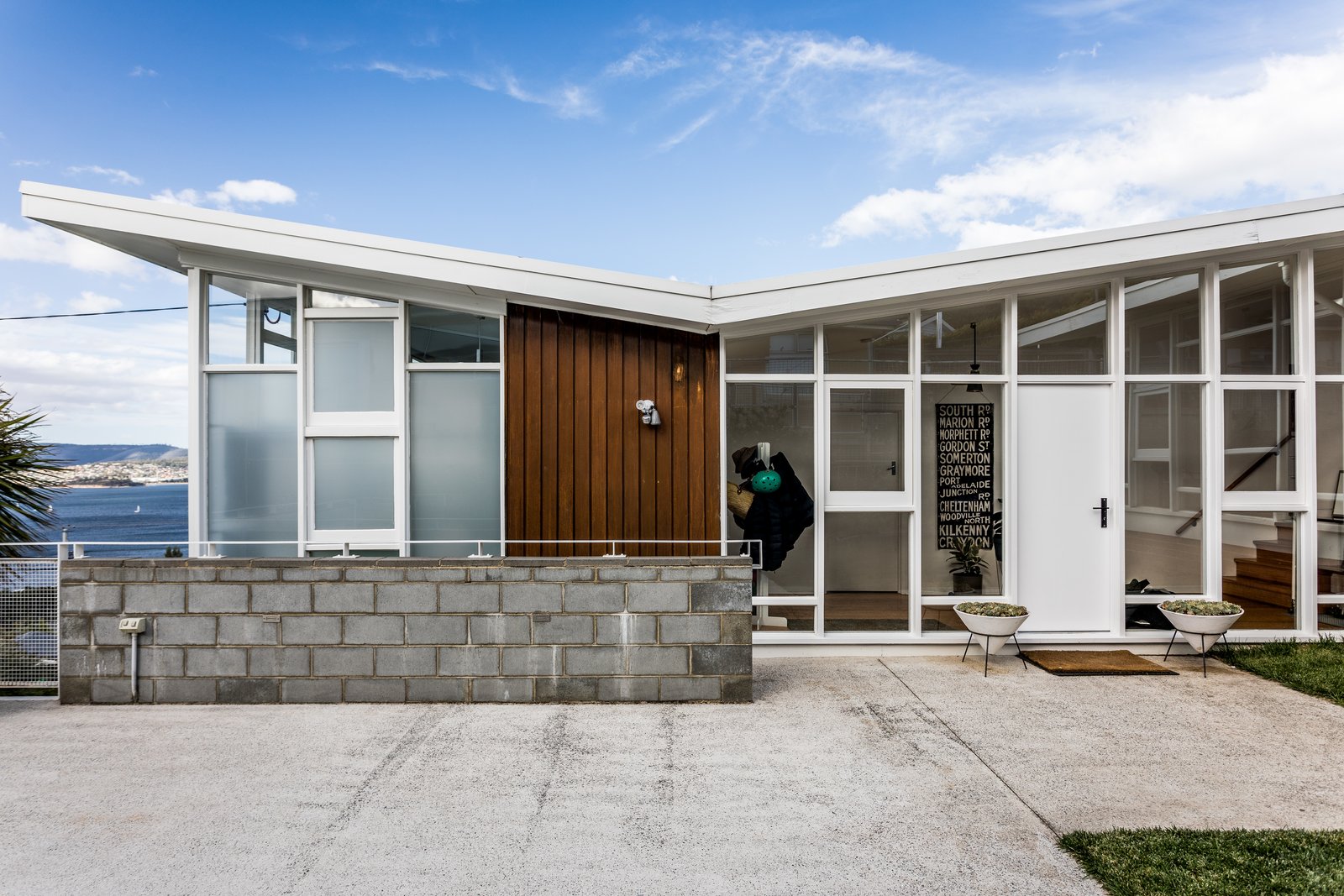 The original house is shaped like an L, with a butterfly roof. The architects first took note of Emery's key material moves, which include the white-framed windows, a brick foundation, and dark hardwood cladding on the exterior. 