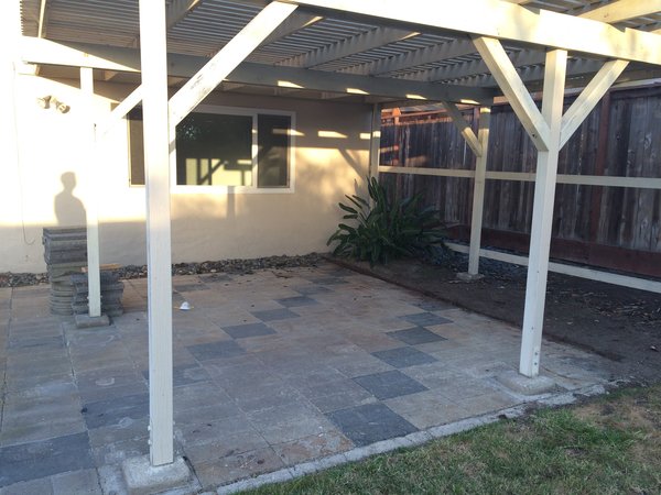 A dated brick pattern lay under the pergola.
