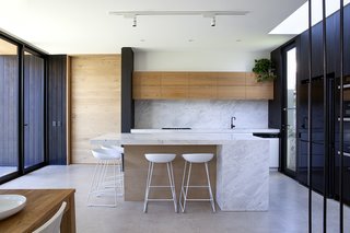 Oak and concrete meet a substantial marble countertop and backsplash in the kitchen.