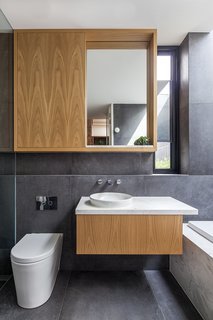 Oak cabinetry topped with marble continues the kitchen's themes in a bathroom.