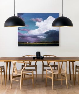 In the dining room, a table custom-made in Denmark by KBH is surrounded by more Wishbone Chairs. The oversized pendants are from Luminaire Authentik.