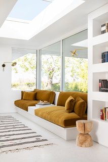 A custom built-in sofa upholstered in whiskey-colored velvet from Fabricut now makes for the perfect reading spot. The swing arm sconces are from Photonic Studio.