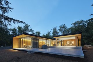 The rear courtyard appears to float over the site. On the right is a large screened porch with three walls of retractable insect screens from Phantom Screens, which make it easy to use the space whether it's bug season or not.