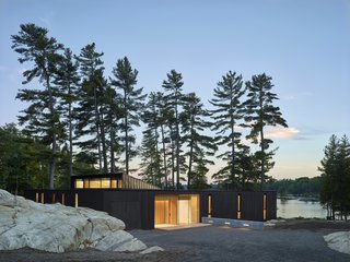 The low-lying home, completed in 2018, sits behind a stand of pine trees just steps from the water. 