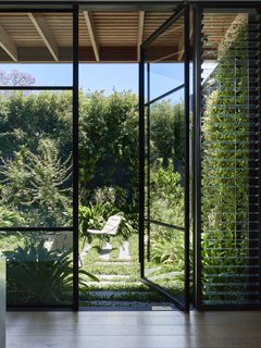 A wall of glazing across from the kitchen pod connects to a centrally located courtyard, with landscaping by Eckersley Garden Architecture.