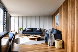 In the living room, the timber joinery continues and creates a sense of enclosure. The architects lined the opposite wall with a continuous bench seat to unify the open plan.